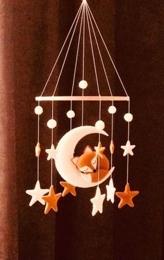 a baby crib mobile with a fox sleeping on the moon and stars hanging from it