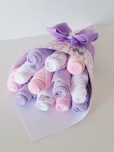 a bunch of baby socks in a purple and white bag with a bow on the top