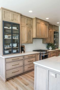 a large kitchen with wooden cabinets and white counter tops, along with hardwood flooring