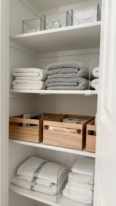 an organized closet with white linens and folded towels in bins on the shelves