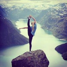 a woman doing yoga on top of a mountain