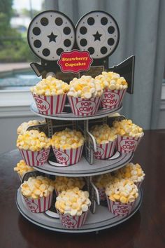 three tiered trays filled with cupcakes and popcorn