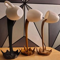 three white and black lamps sitting on top of a wooden table next to each other