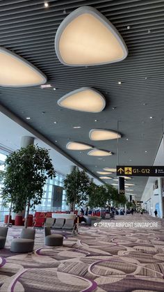 an airport terminal with people walking around and sitting on chairs in the middle of it