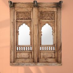 an old wooden double door with mirrors on the front and back doors, hanging against a pink wall