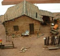 a small house made out of bricks and wood with tools on the ground next to it