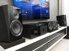 there are many speakers on the shelf in front of the flat screen tv and sound system