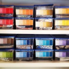 the shelves are filled with many different colored paint samples in plastic bins and on top of each other