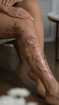 a woman sitting on the floor with her legs crossed and tattoos on her leg,