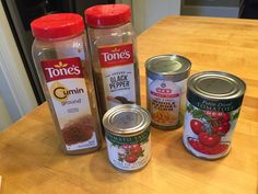 spices and seasonings are sitting on a counter top next to cans of tomatoes, garlic, cumin, ground beef