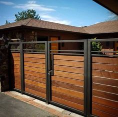 a wooden fence with metal bars on the top and bottom, in front of a house