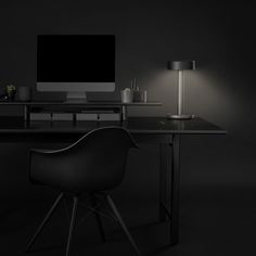 a black desk with a computer on it and a chair next to it in the dark