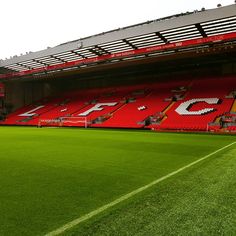 an empty soccer field with red seats and green grass