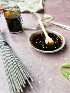 an assortment of cooking utensils sit on a table next to a bowl of sauce