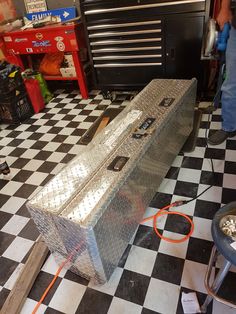 a metal box sitting on top of a black and white checkered floor in a garage