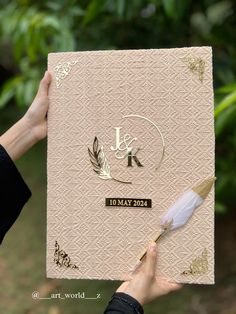 a person holding up a book with a feather on it and the word love written in gold