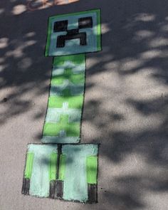 a street sign painted on the side of a road next to a sidewalk with trees in the background