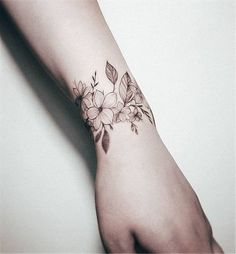 a woman's arm with flowers and leaves tattooed on the left side of her wrist