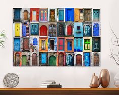 an assortment of multicolored doors on a white wall above a table with vases