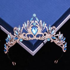 a tiara with blue and white stones on it sitting next to a book that is open