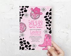 a hand holding up a pink and black birthday card with cowgirl boots on it