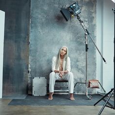 a woman is sitting on a bench in front of a camera and light set up