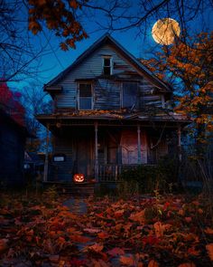 an old house with a full moon in the background and leaves on the ground around it