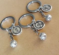 three silver key chains with soccer balls and numbers on them sitting on top of a table