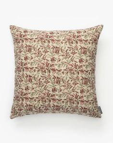 a red and white floral pillow on a white background