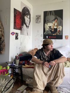 a young man sitting on top of a bed in a room with posters above him