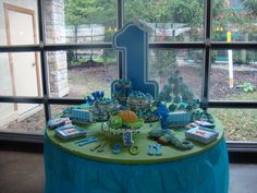 a table that has some kind of cake on it with blue and green decorations around it