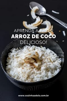 a bowl filled with white rice next to a spoon and fork on top of a table