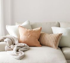 a white couch with pillows and blankets on it