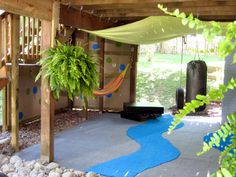 an outdoor area with hammock, rocks and plants on the ground in front of it