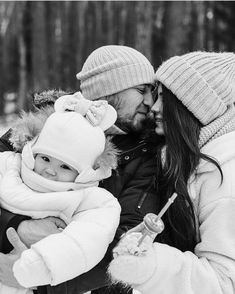 a man and woman holding a baby in the snow