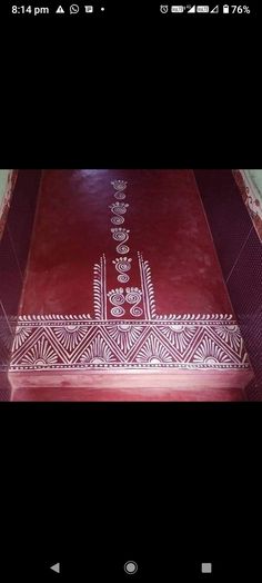 a red table with white designs on the top and bottom, in front of a black background