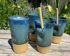 four blue cups with toothbrushes in them on a wooden table next to flowers