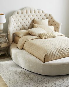 a large round bed sitting on top of a wooden floor next to a white wall