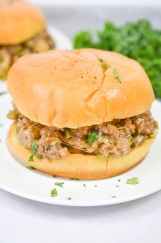 two hamburgers with meat and vegetables on a white plate next to some parsley