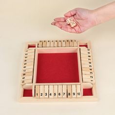 a hand is holding a wooden abacus with numbers on it and a red tray