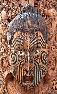 an intricately carved wooden mask with many faces and designs on it's face