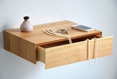 a wooden drawer with a cell phone and chain hanging from it's bottom shelf