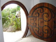 an open wooden door with wrought iron work on it's side and another round window in the background