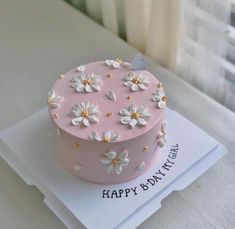 a pink birthday cake with white flowers on it