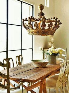 a wooden table with chairs around it and a chandelier hanging from the ceiling