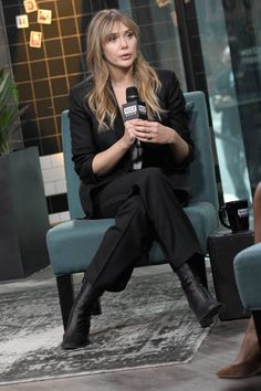 a woman sitting in a chair holding a microphone and talking to someone on the other side