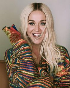 a woman with blonde hair and blue eyes is holding her hands up to her face