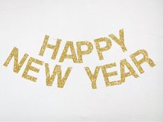 the words happy new year written in gold glitter on a white background with an arrow