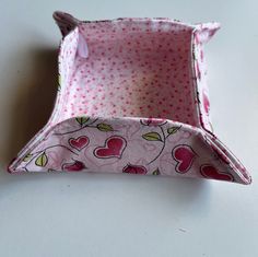 a pink and white polka doted fabric box with hearts on the inside, sitting on a table