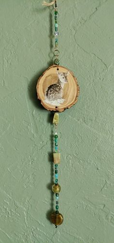 an owl is sitting in the center of a piece of wood with beads hanging from it